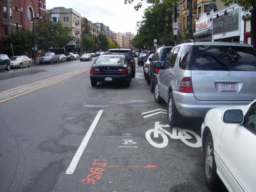 Holy wow!  Two double parkers, with the sharrow being parked on...how in the hell does this mean "share the road"